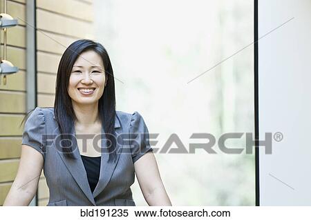 Stock Photography - Asian businesswoman smiling in office. Fotosearch