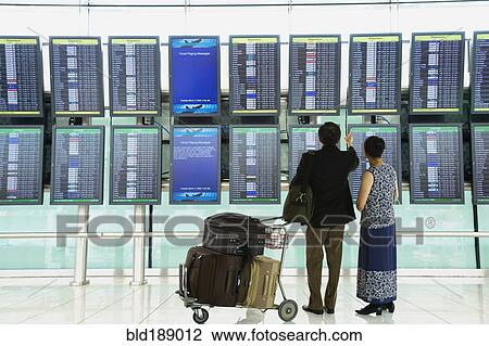 Asian couple checking flight schedules in airport View Large Photo Image Stock Image - Asian couple checking flight schedules in airport. Fotosearch