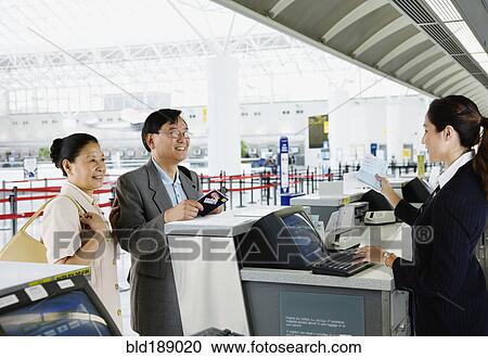 Stock Image - Asian couple checking in at airport. Fotosearch