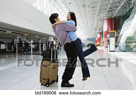 Stock Photo - Asian couple hugging in airport. Fotosearch