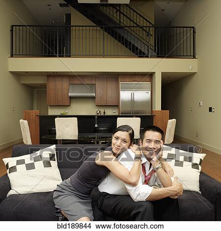 Picture - Asian couple hugging on sofa. Fotosearch