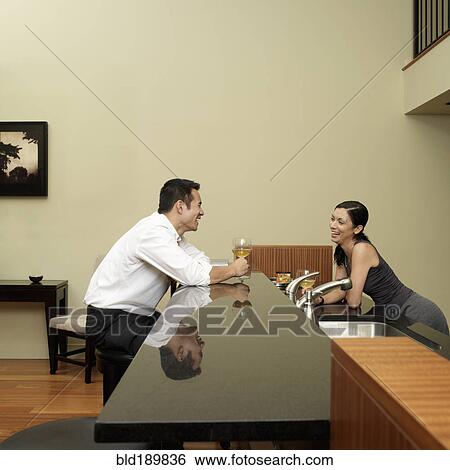 Stock Photograph - Asian couple talking in kitchen. Fotosearch