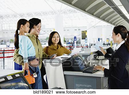 Stock Image - Asian family checking in at airport. Fotosearch