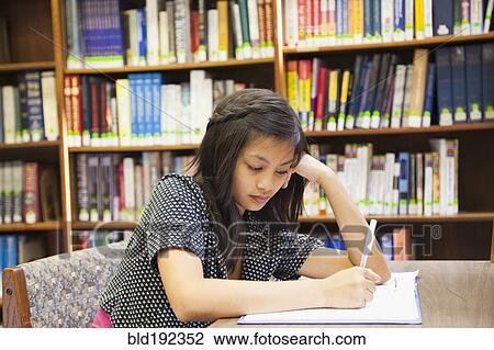 Stock Image - Asian girl doing homework in library. Fotosearch