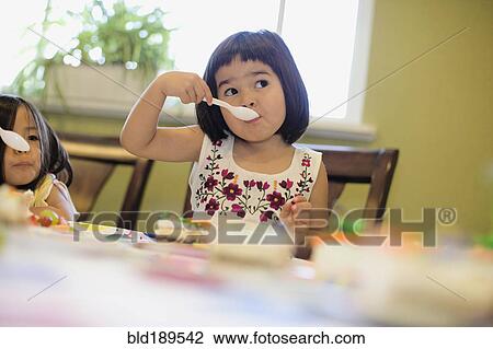 Stock Image - Asian girls eating cake. Fotosearch