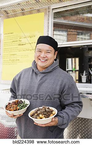 Asian man holding bowls of food at food truck View Large Photo Image Stock Photo - Asian man holding bowls of food at food truck. Fotosearch