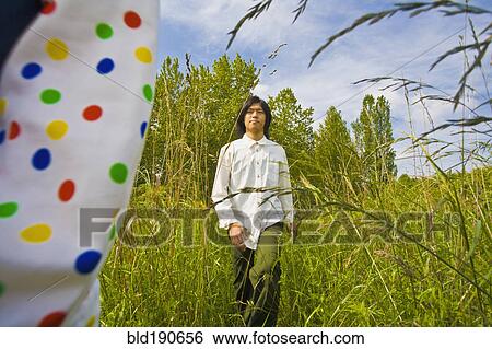 Asian man walking through tall grass View Large Photo Image Stock Photograph - Asian man walking through tall grass. Fotosearch
