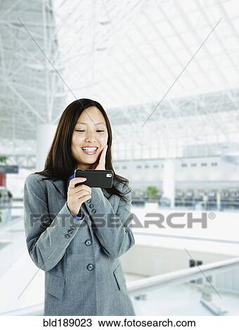Asian woman checking cell phone in airport View Large Photo Image Stock Image - Asian woman checking cell phone in airport. Fotosearch