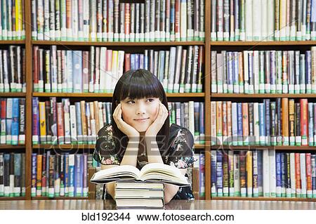 Picture - Asian woman daydreaming in library. Fotosearch