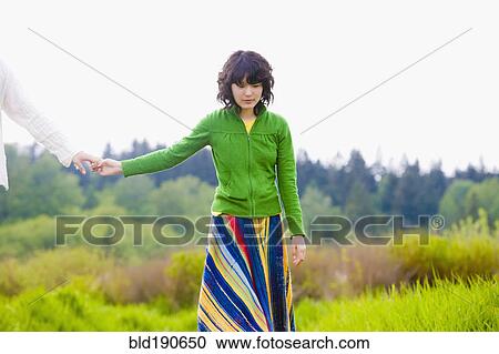 Stock Image - Asian woman holding boyfriend's hand. Fotosearch
