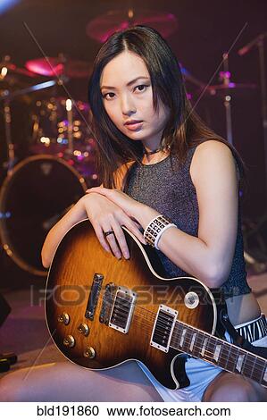 Stock Image - Asian woman holding electric guitar. Fotosearch