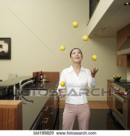 Stock Photo - Asian woman juggling lemons in kitchen. Fotosearch