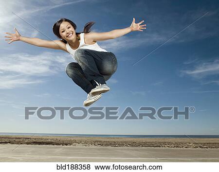 Stock Photo - Asian woman jumping in air. Fotosearch