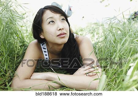Stock Photo - Asian woman laying in grass. Fotosearch