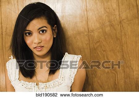 Stock Image - Asian woman leaning against wall. Fotosearch