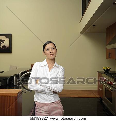 Stock Photo - Asian woman leaning on counter in kitchen. Fotosearch