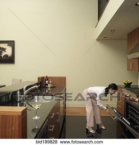 Asian woman looking in oven View Large Photo Image Stock Photo - Asian woman looking in oven. Fotosearch
