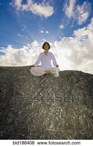 Asian woman meditating on rock View Large Photo Image Stock Photo - Asian woman meditating on rock. Fotosearch