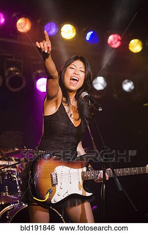 Asian woman singing and playing electric guitar onstage View Large Photo Image Stock Photograph - Asian woman singing and playing electric guitar onstage. Fotosearch