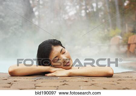 Stock Photo - Asian woman sitting in hot tub. Fotosearch