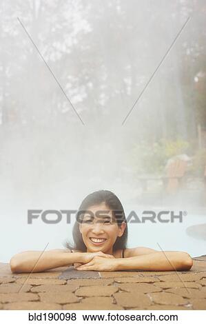 Stock Photo - Asian woman sitting in hot tub. Fotosearch