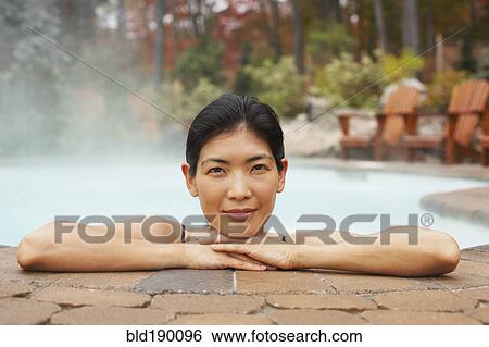 Stock Photograph - Asian woman sitting in hot tub. Fotosearch