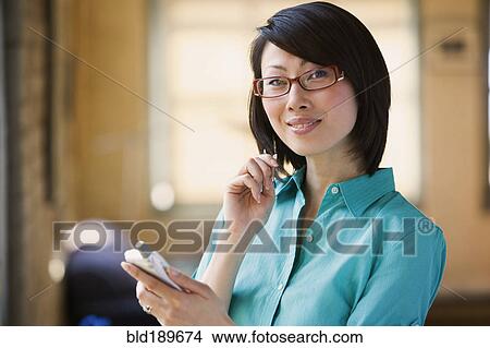 Picture - Asian woman smiling with electronic organizer. Fotosearch