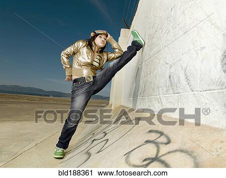 Stock Image - Asian woman stretching leg on wall. Fotosearch