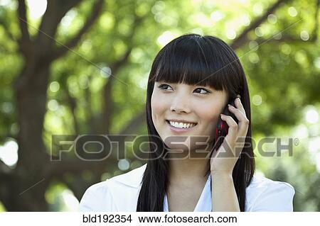 Picture - Asian woman talking on cell phone. Fotosearch