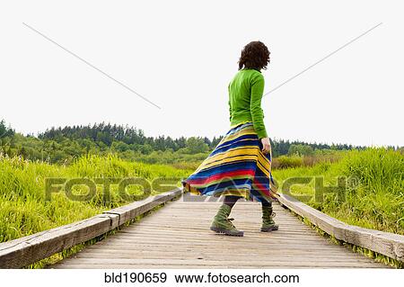 Stock Photo - Asian woman walking on wooden path. Fotosearch