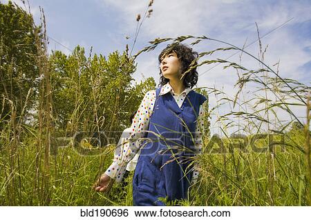 Asian woman walking through tall grass View Large Photo Image Stock Photograph - Asian woman walking through tall grass. Fotosearch
