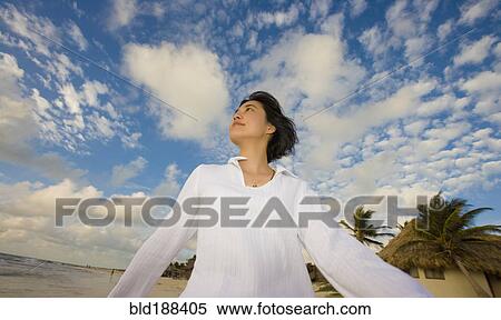 Stock Photography - Asian woman walking under blue sky with clouds. Fotosearch