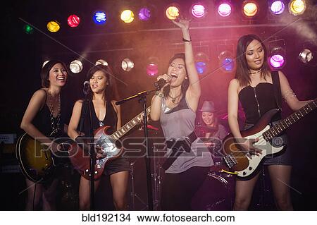 Picture - Asian women singing and playing guitar onstage. Fotosearch