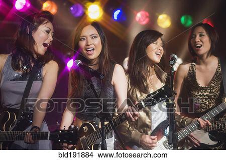 Picture - Asian women singing and playing electric guitar onstage. Fotosearch