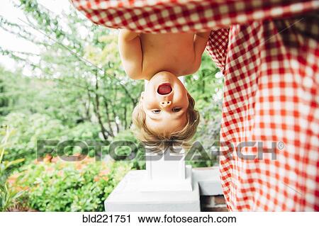 Stock Image - Baby boy hanging upside down outdoors. Fotosearch