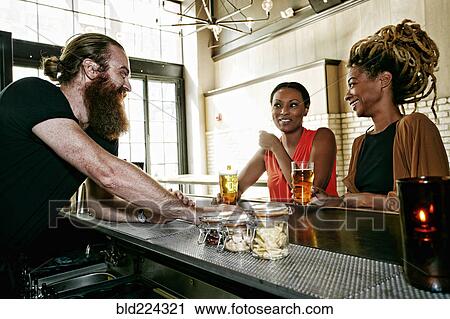 Bartender talking to customers View Large Photo Image Stock Image - Bartender talking to customers. Fotosearch