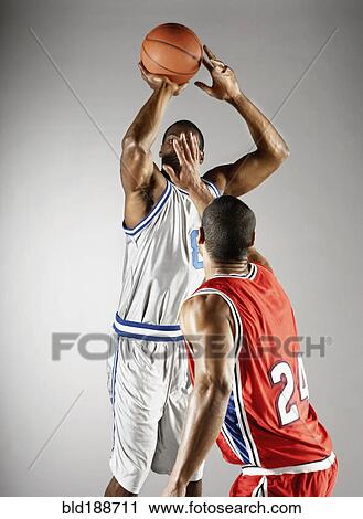 Stock Image - Basketball player trying to take basketball from opponent. Fotosearch