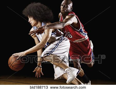 Stock Image - Basketball player trying to take basketball from opponent. Fotosearch