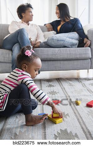 Stock Photography - black baby girl playing on carpet with blocks. Fotosearch