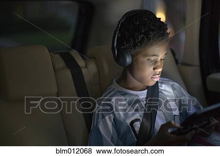 Stock Photo - Black boy playing video game in car at night. Fotosearch