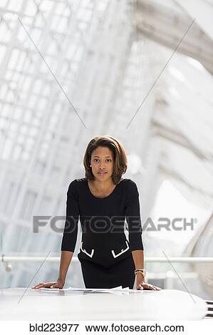 Stock Photo - Black businesswoman leaning over paperwork conference room. Fotosearch