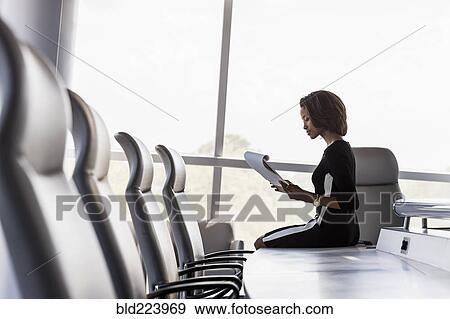 Black businesswoman sitting on conference table reading notepad View Large Photo Image Stock Photo - Black businesswoman sitting on conference table reading notepad. Fotosearch
