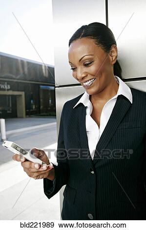 Stock Photo - Black businesswoman using cell phone outdoors. Fotosearch