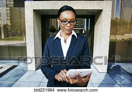 Picture - Black businesswoman using digital tablet outdoors. Fotosearch
