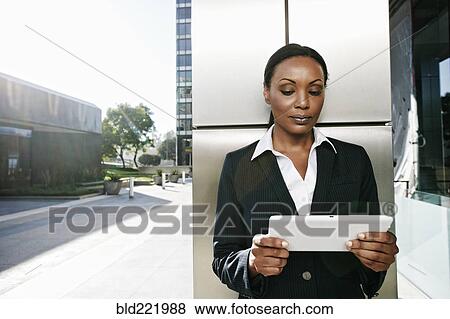 Stock Photo - Black businesswoman using digital tablet outdoors. Fotosearch