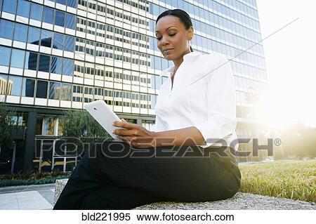Stock Photography - Black businesswoman using digital tablet outdoors. Fotosearch