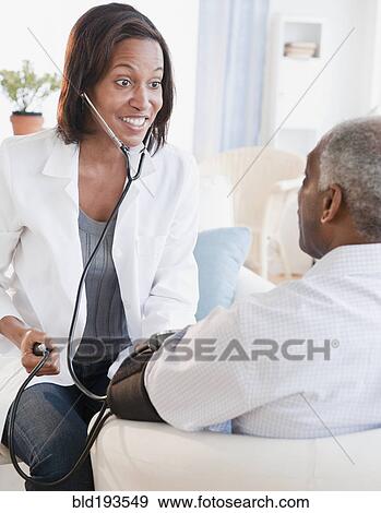 Black doctor checking senior man's blood pressure View Large Photo Image Stock Photo - Black doctor checking senior man's blood pressure. Fotosearch