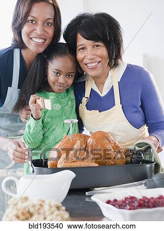 Stock Image - Black family preparing Thanksgiving dinner. Fotosearch