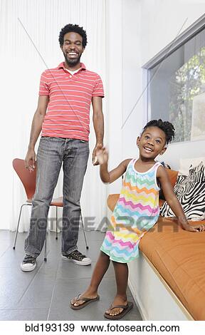 Stock Photo - Black father and daughter in living room. Fotosearch