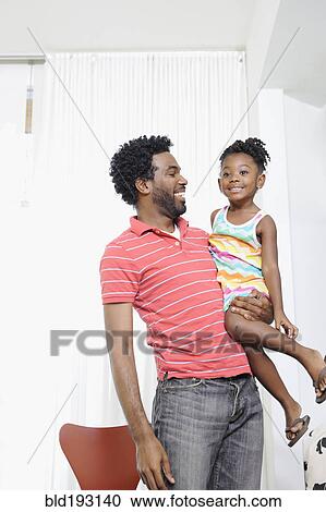 Stock Image - Black father holding daughter. Fotosearch